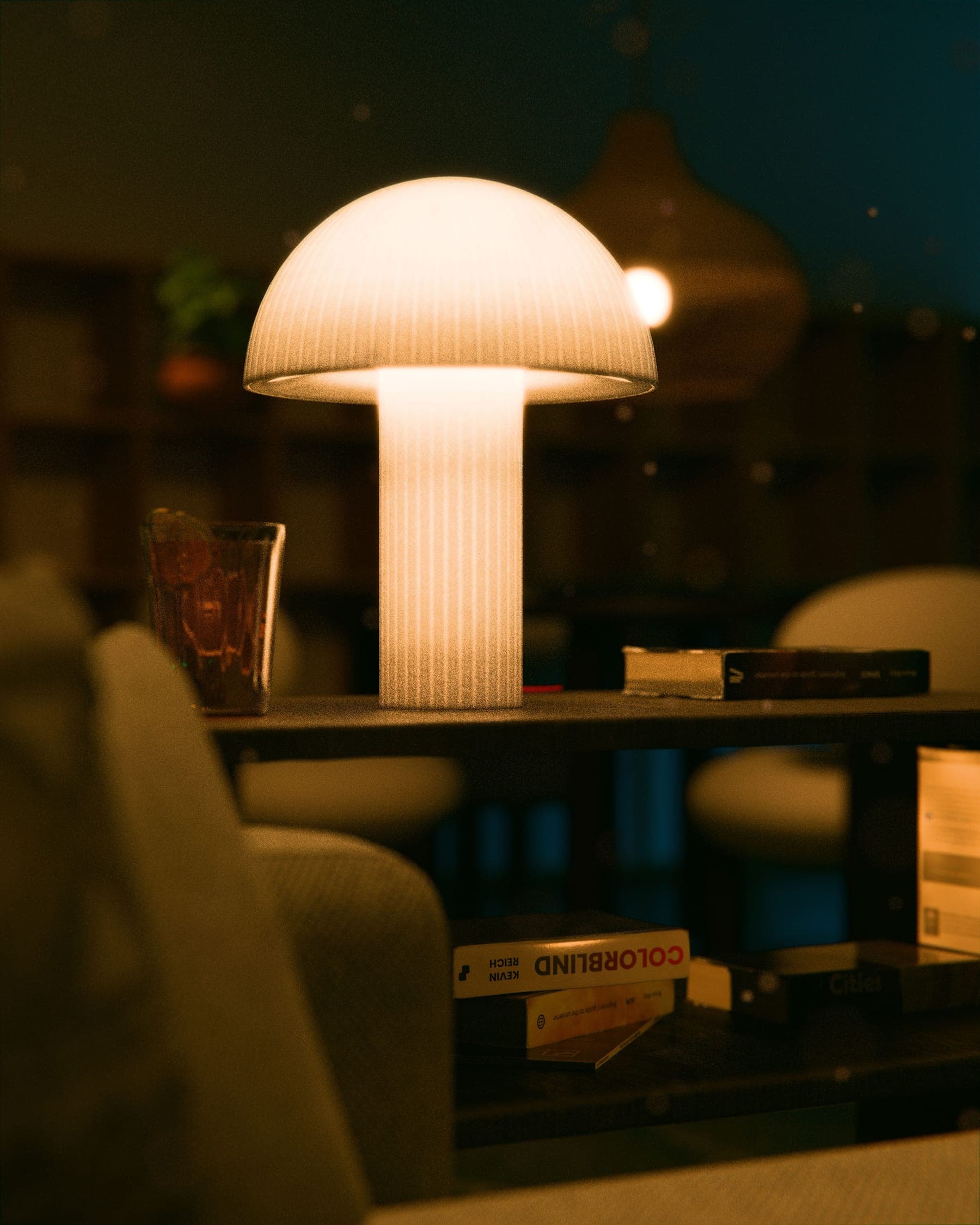 A ribbed, dome-shaded 3D-printed table lamp glowing warmly on a shelf